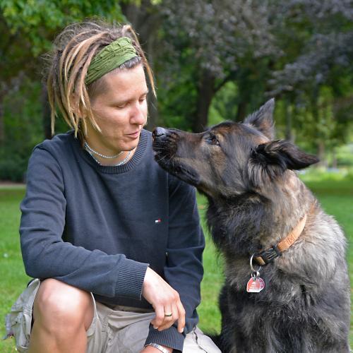 Alex Bikowski kniet neben Hündin Paula und sie schauen sich gegenseitig an.